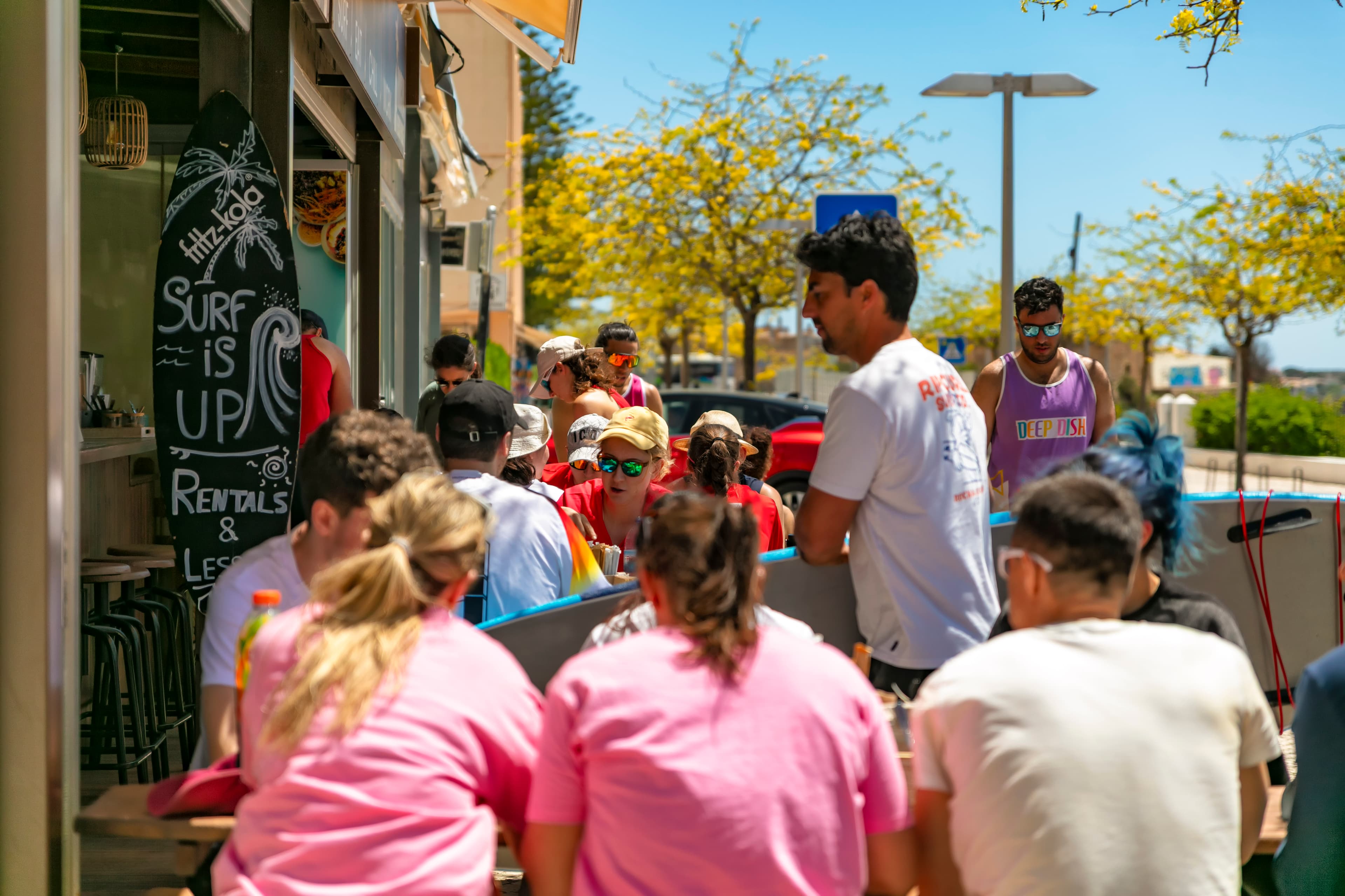 Rocha Beach House outside view with people sitting outside and someone walking inside with their surfborard.