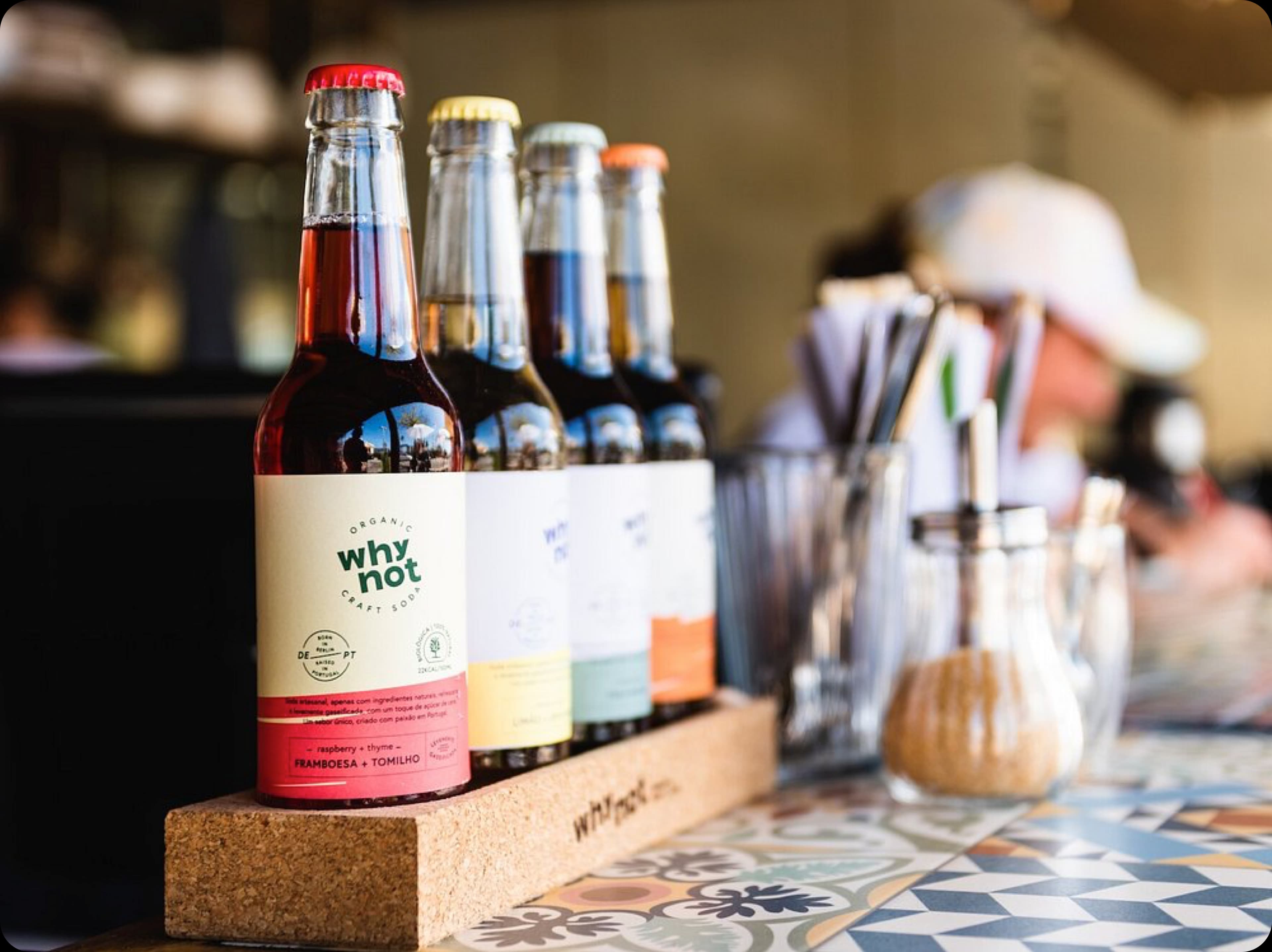 A selection of artisanal bottled drinks, like kombucha or fresh juices, on a tiled bar counter.