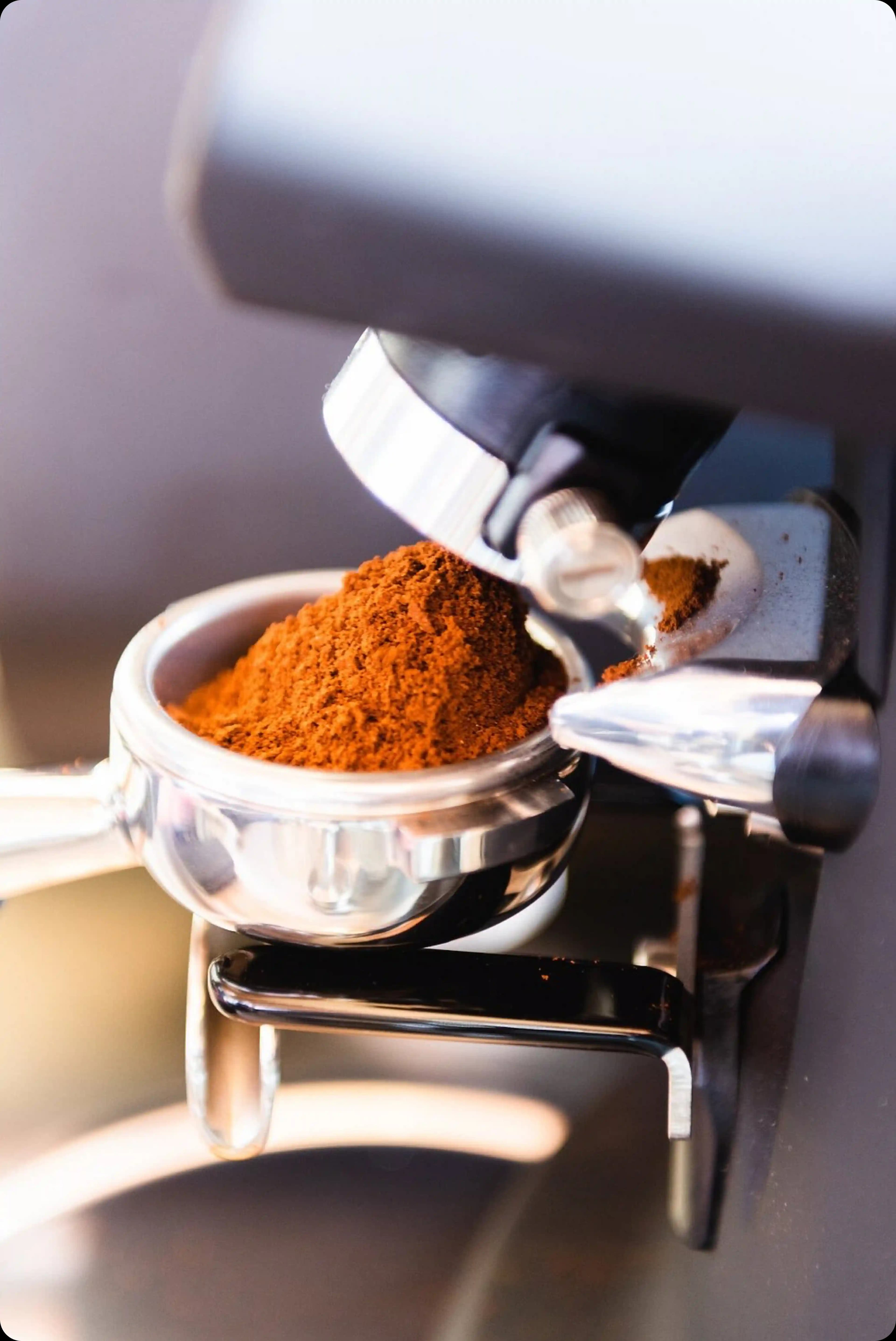 A close-up of an espresso machine's portafilter filled with a mound of fresh coffee grounds.